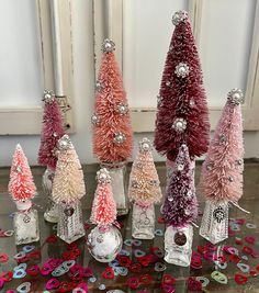 a group of small christmas trees sitting on top of a table next to confetti