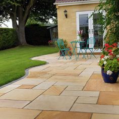 a patio with chairs, table and potted plants on the side of the house