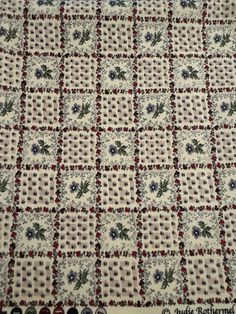 a quilted table cloth with flowers and leaves on the edges, in white and red colors