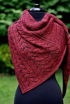 a woman wearing a red knitted shawl on top of a black mannequin