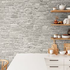 a kitchen with stone wallpaper and white counter tops, along with wooden shelves filled with dishes