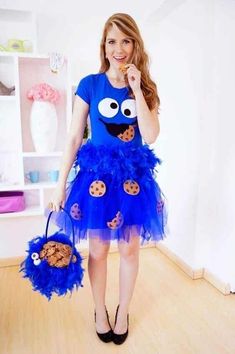 a woman wearing a cookie monster costume and holding a cookie in her hand while posing for the camera