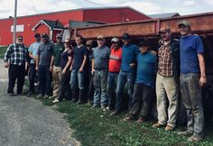 a group of men standing next to each other in front of a dump truck on grass