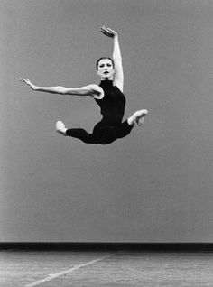 a black and white photo of a woman jumping in the air