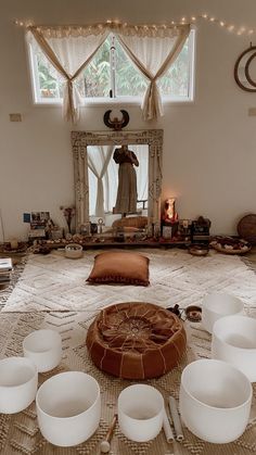 there are bowls and cups on the floor in front of a large mirror with lights