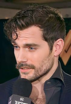 a close up of a person wearing a suit and tie with a microphone in front of him