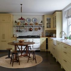 a kitchen with yellow cabinets and white appliances in the center, along with a round rug on the floor