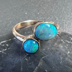 Two stone Australian opal ring set in solid 14k gold.  Double opal ring, with dark opal and crystal opal in 14k yellow gold. US Size 6 1.05 total carats Australian opal from Lightning Ridge. Oval stone is N6 dark opal the round stone is a crystal. 2.5mm x 1.3 mm solid 14k gold band and bezel. All of our creations are made out of 14K Gold (Yellow, White, Rose) or 925 Sterling Silver, None are filled or electroplated.  All of our stones are Nature-made, therefore some natural flaws may be present. Opal Birthstone Ring Oval Cabochon, Polished Opal Ring In Oval Cabochon Shape, Opal Oval Cabochon Ring With Polished Finish, Polished Opal Oval Cabochon Ring, Opal Rings With Polished Finish For Anniversary, Opal Open Ring Birthstone, Adjustable Opal Gemstone Ring, Handmade Open Opal Ring, Ethiopian Opal Multi-stone Ring