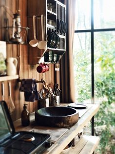 a stove top oven sitting next to a wooden shelf filled with utensils and pans