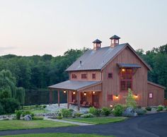 a large red barn sitting in the middle of a lush green field next to trees