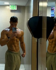 a shirtless man taking a selfie in front of a mirror with his cell phone