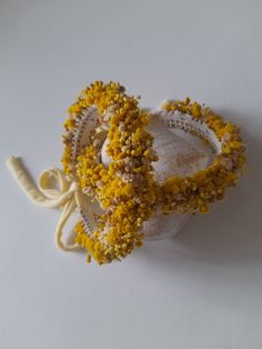 two bracelets made out of yellow flowers on a white surface with a string attached to them