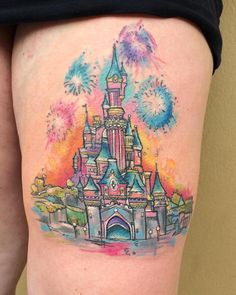 a woman's thigh with a colorful castle tattoo on her left leg and fireworks in the sky above it