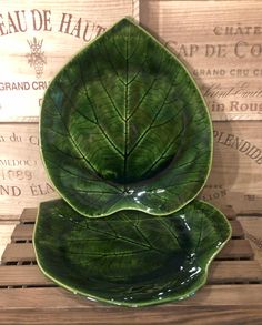 two green leaf shaped dishes sitting on top of a wooden table