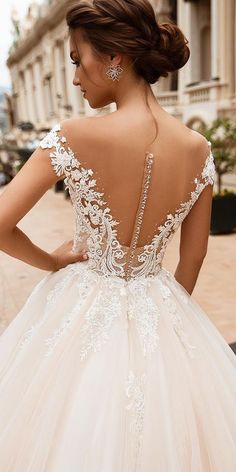 a woman wearing a wedding dress with an open back and beading on the shoulders