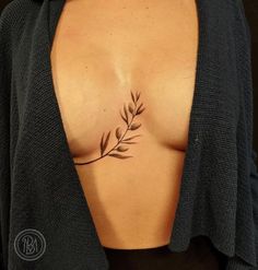 a woman's chest with an olive branch tattoo on her left side ribcage