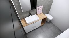 a white sink sitting next to a toilet in a bathroom on top of a wooden counter