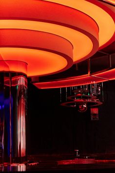 the ceiling is lit up with red lights and circular fixtures in an empty room at night