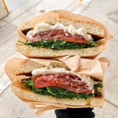 two sandwiches with meat, cheese and spinach on them sitting on top of each other