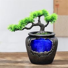 a bonsai tree in a blue vase with water and moss growing on it's sides