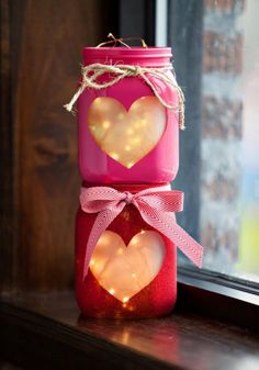 two mason jars with hearts are sitting on a window sill