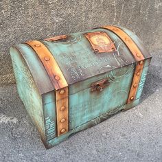 an old trunk is sitting on the ground next to a concrete wall and cement floor