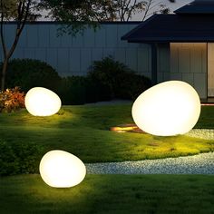 three glowing balls on the grass in front of a house