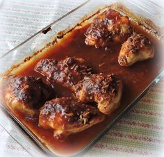 a glass dish filled with meat covered in gravy on top of a table