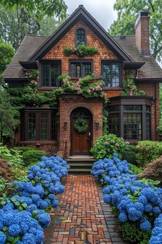 a brick house with blue hydrangeas in the front yard