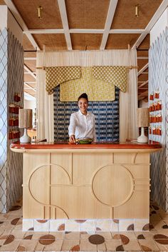 a man standing behind a wooden counter in a room with tile flooring and walls