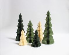 four green and white paper christmas trees on a white background with one folded in the shape of an origami tree