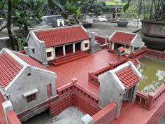 a model of a house with red roof tiles and water in the yard, surrounded by greenery