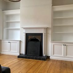 an empty living room with white bookcases and a fireplace