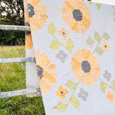 a quilt hanging on a fence in the grass