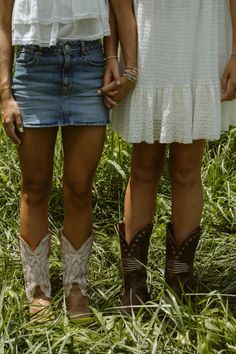 two people standing next to each other in the grass with cowboy boots on their feet