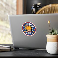 a laptop computer sitting on top of a wooden desk next to a potted plant