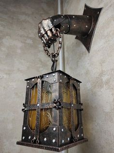 an old fashioned lantern hanging from a hook on a wall with chain attached to it