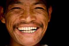 a close up of a smiling man with white teeth