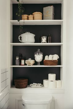 a white toilet sitting in a bathroom next to shelves