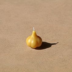 a yellow onion sitting on top of a sandy beach next to a small white object