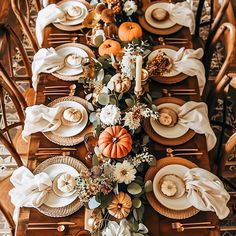 the table is set with plates, napkins and pumpkins