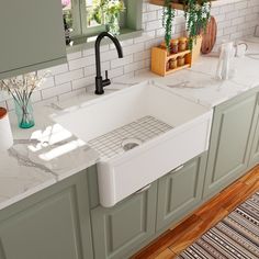 a white kitchen sink sitting under a window next to a counter top with green cabinets