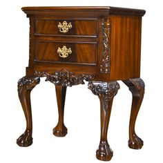 an ornately carved wooden cabinet with drawers and legs on one side, in the shape of a lion's paw