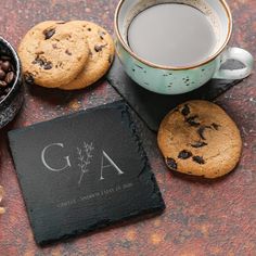 cookies, chocolate chips and coffee are sitting on a table next to a slate coaster