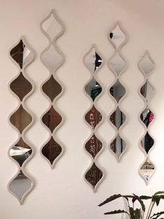 three decorative mirrors hanging on the wall next to a potted plant in a living room