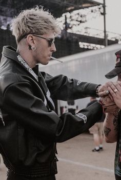 two people standing next to each other with tattoos on their arms and one person holding the other's hand