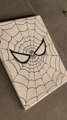 a spider - man's face is drawn on a white tile with black lines