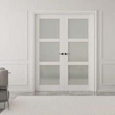 an empty room with white walls and two chairs in front of the glass doors that are open