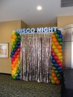 a room filled with balloons and streamers next to a wall that says disco night