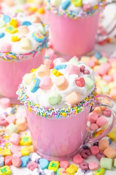 two pink mugs filled with colorful sprinkles and marshmallows